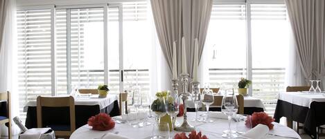 A dining area with tables set for a meal, featuring white tablecloths, silverware, and glassware.