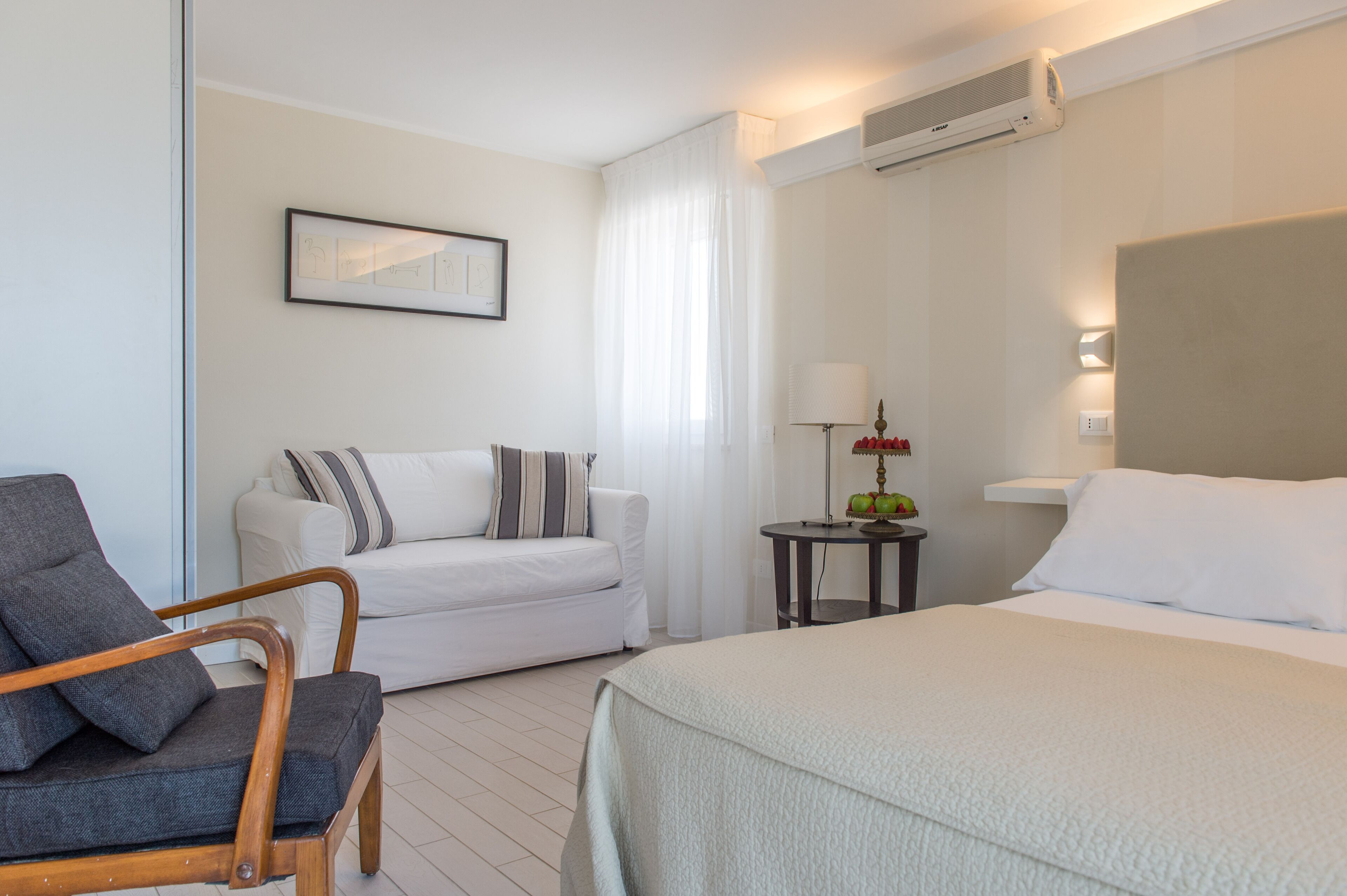 Een hotelkamer met een bed, een bank, een stoel en een kleine tafel met een lamp.