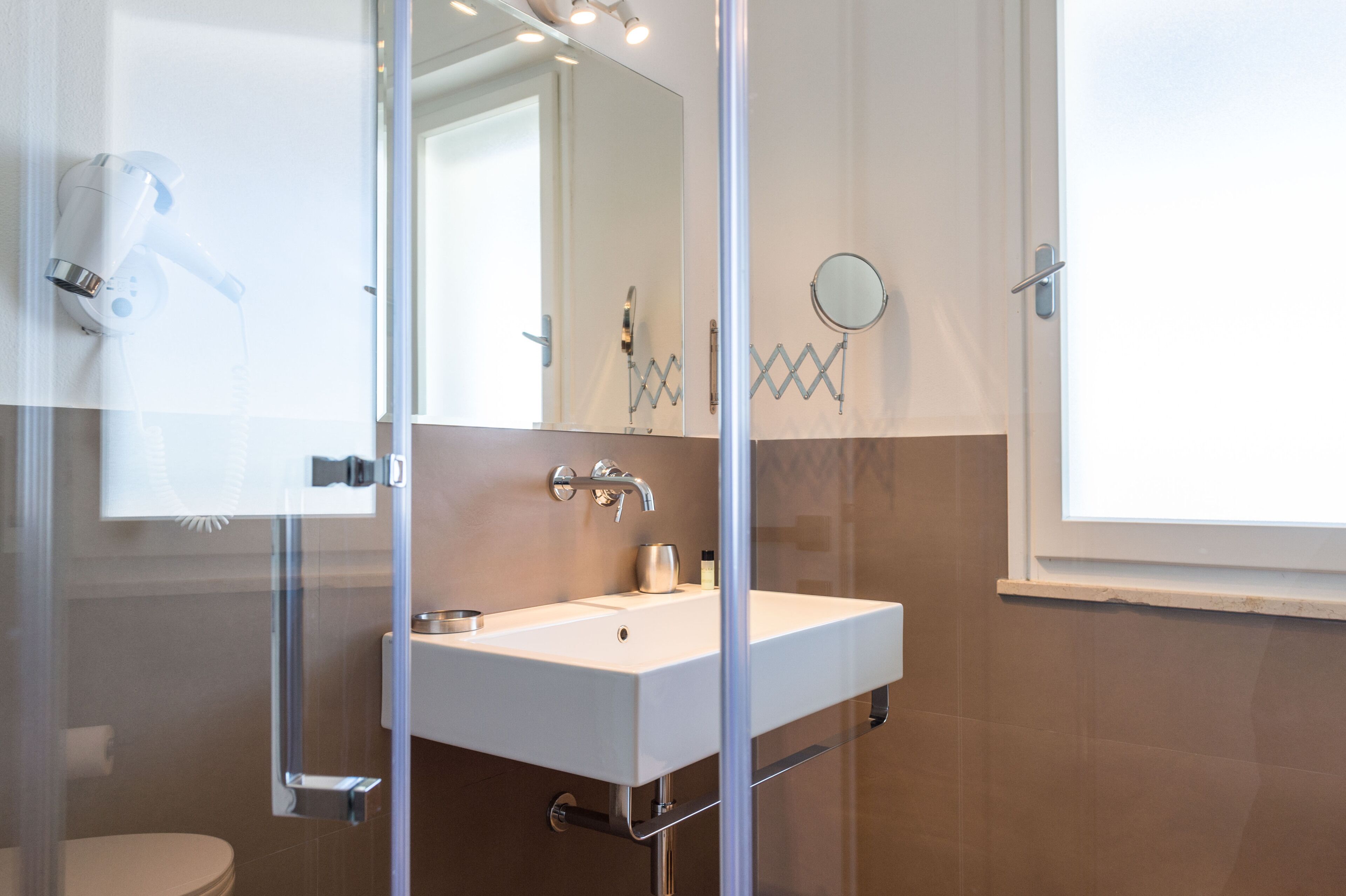 A bathroom with a white sink, a mirror, and a shower area.