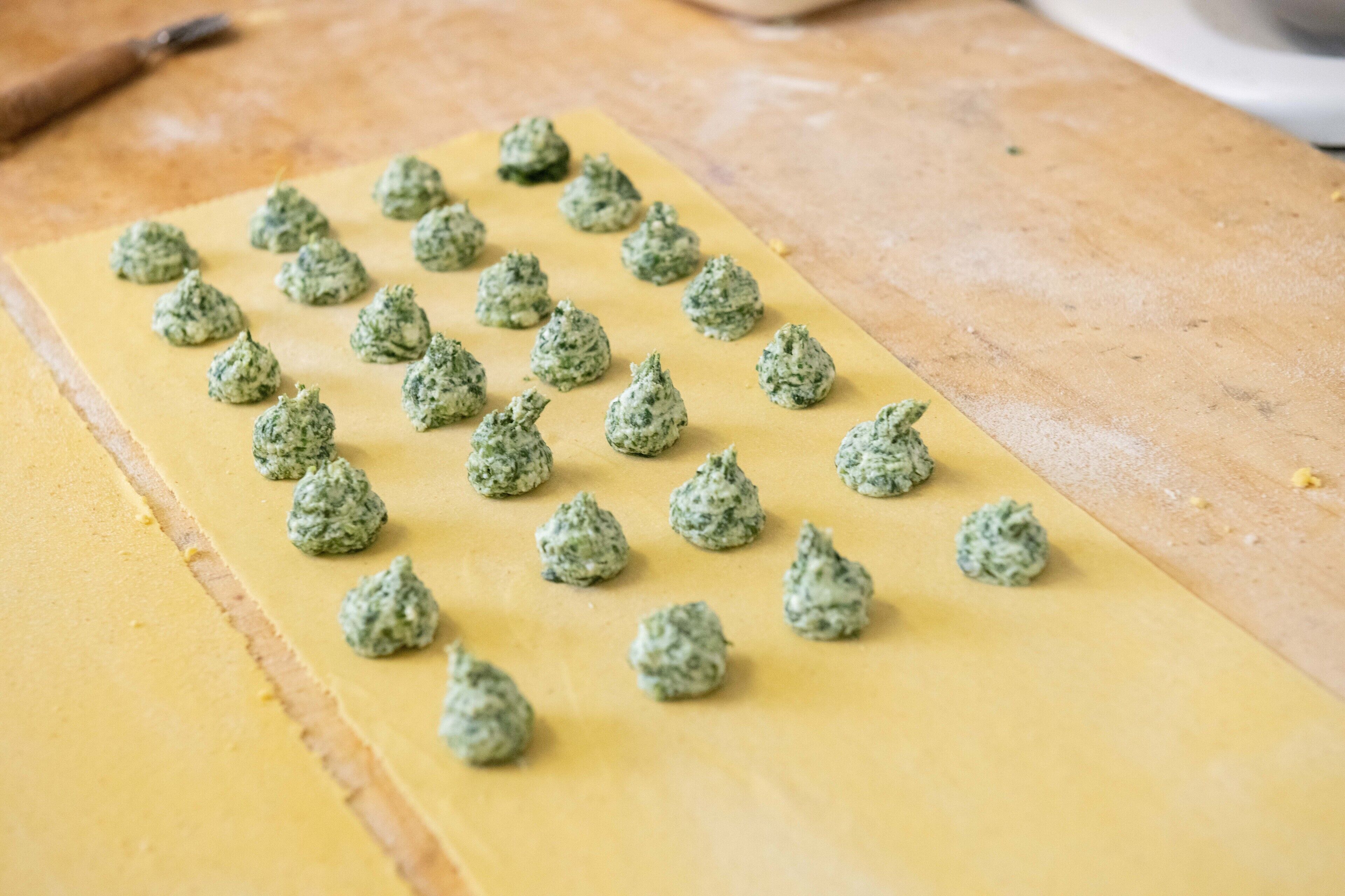 A flatbread with green herb balls on a wooden surface.