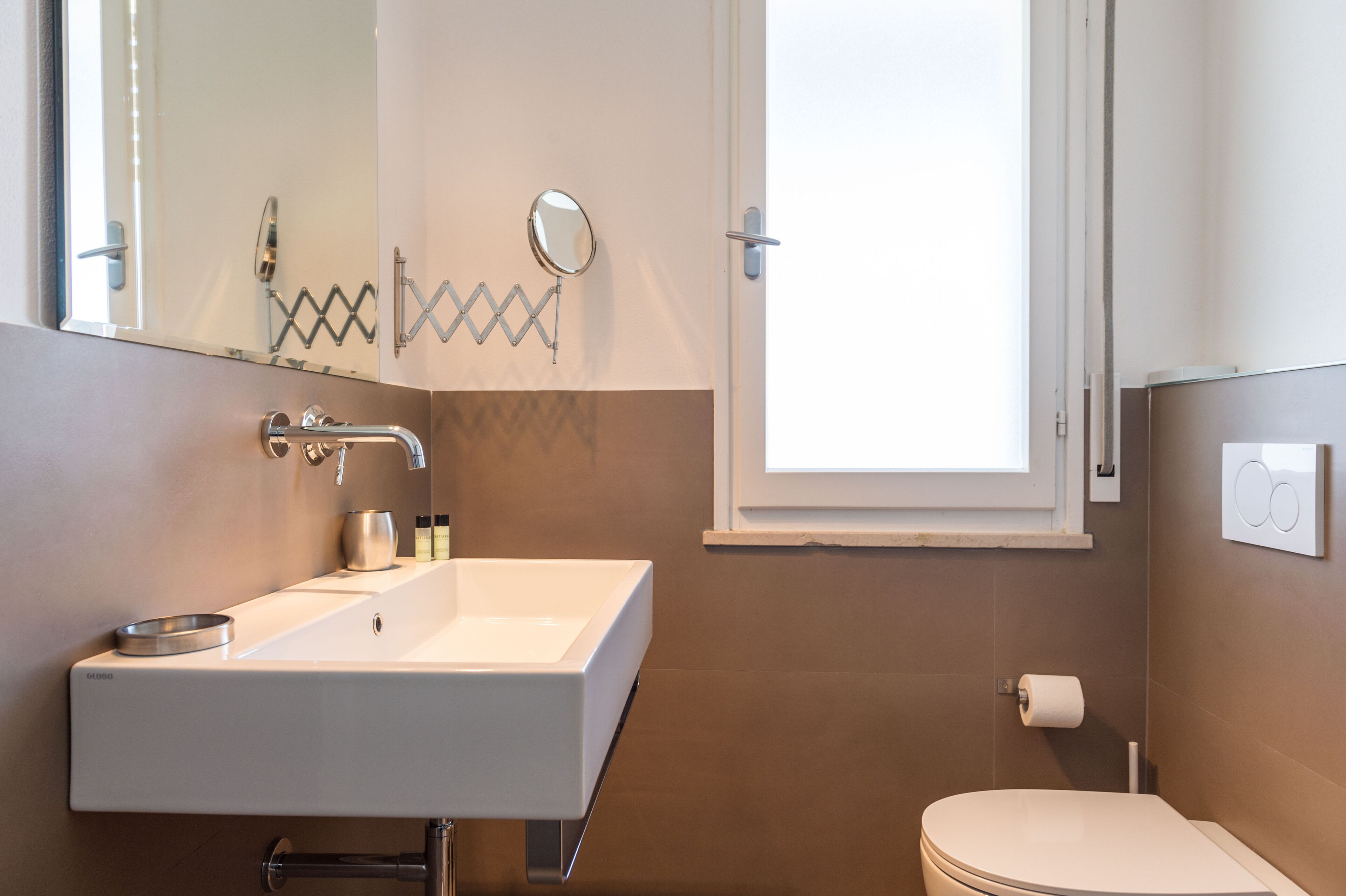 A modern bathroom with a white sink, mirror, and toilet.