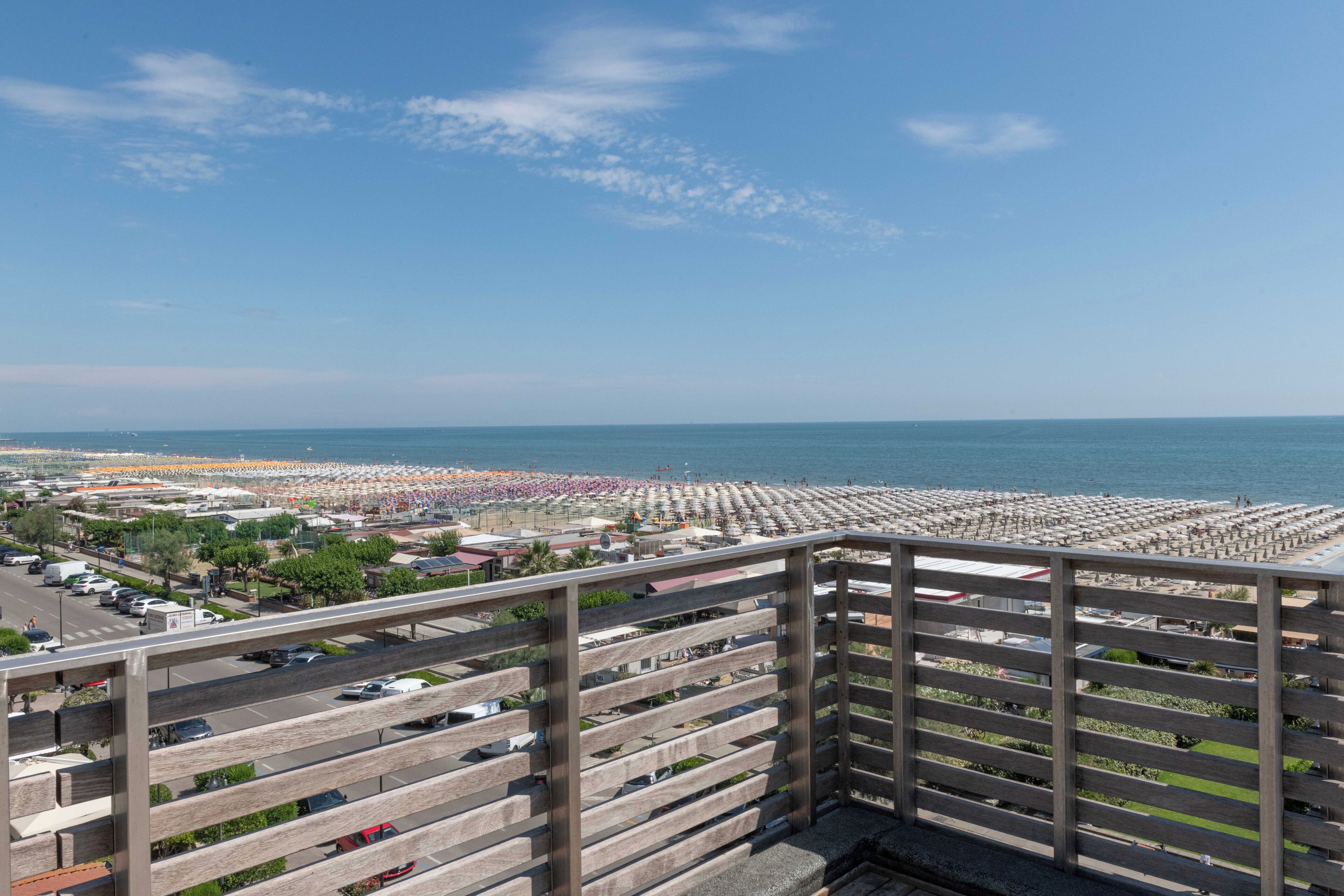 A balcony with a view of a beach and a parking lot.