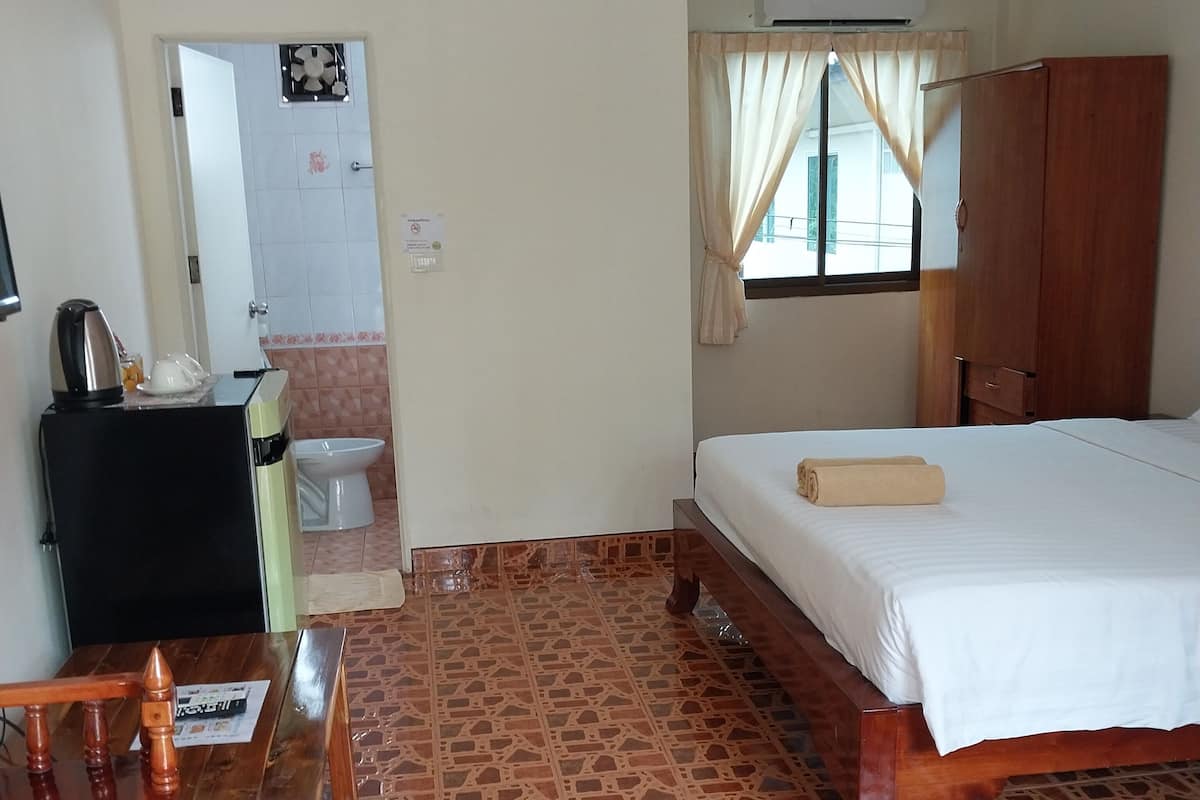 A hotel room with a bed, wooden desk, and a bathroom visible through an open door.