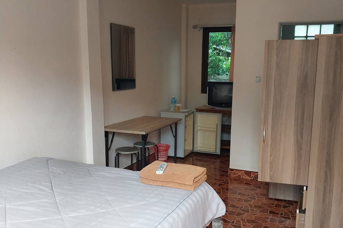 A bedroom with a bed, a desk, a TV, and a wardrobe.