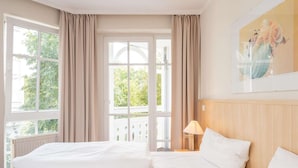 Une chambre d’hôtel avec un grand lit, une table de chevet avec une lampe et une fenêtre avec des rideaux.