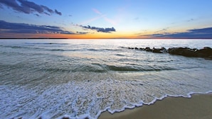 Une plage avec des vagues et un coucher de soleil.