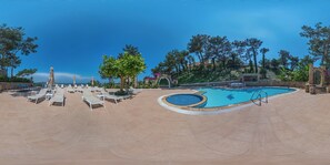 A pool area with lounge chairs, a swimming pool, and surrounding trees.