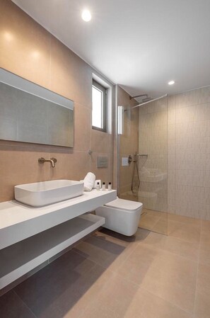 Ein modernes Badezimmer mit einem großen Spiegel, einem weißen Waschbecken, einer Dusche und einer Toilette.