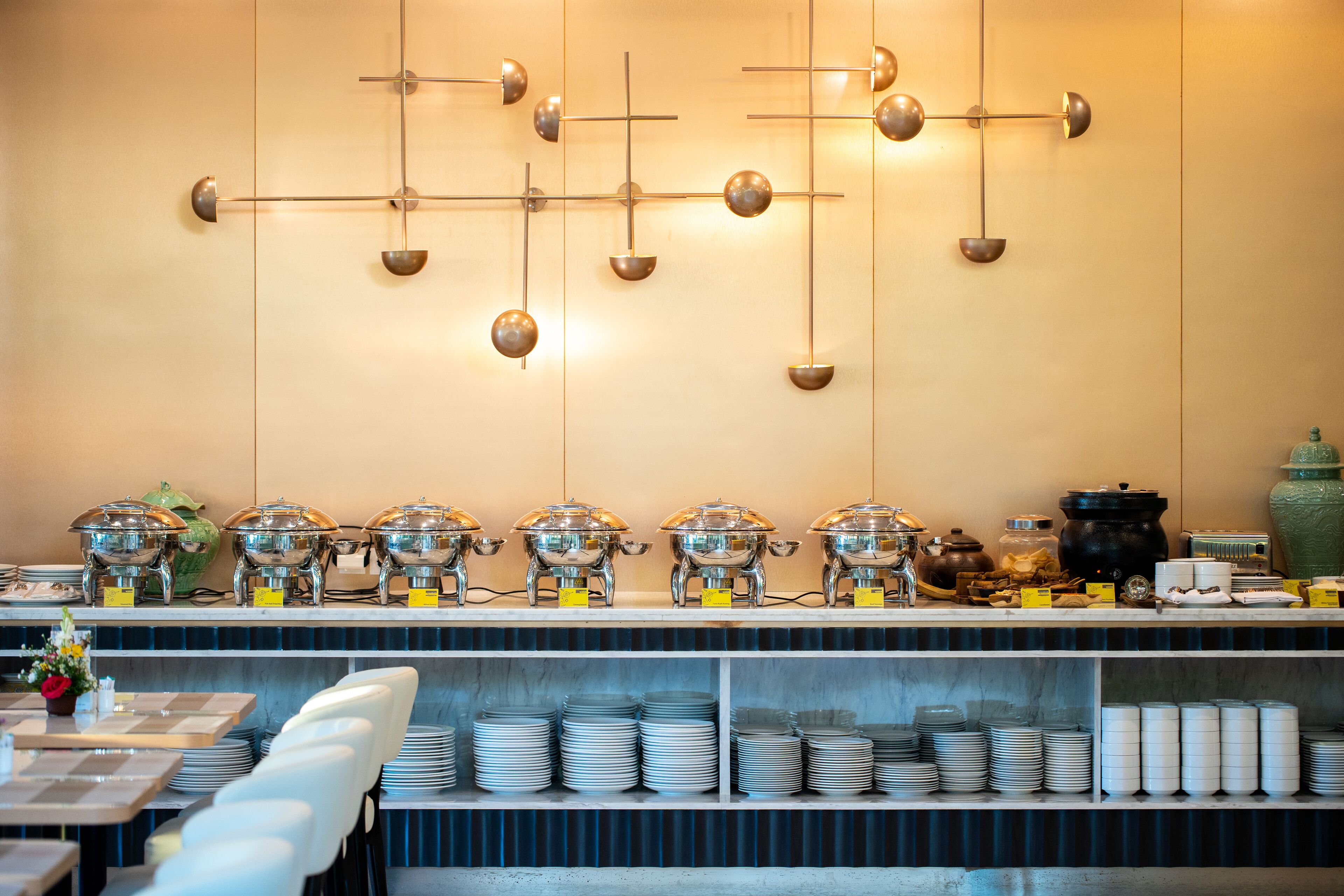 A buffet setup with multiple serving stations, a variety of dishes, and a modern wall decor.