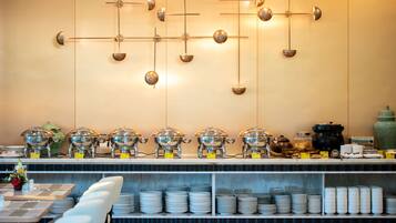 A buffet setup with multiple serving stations, a variety of dishes, and a modern wall decor.