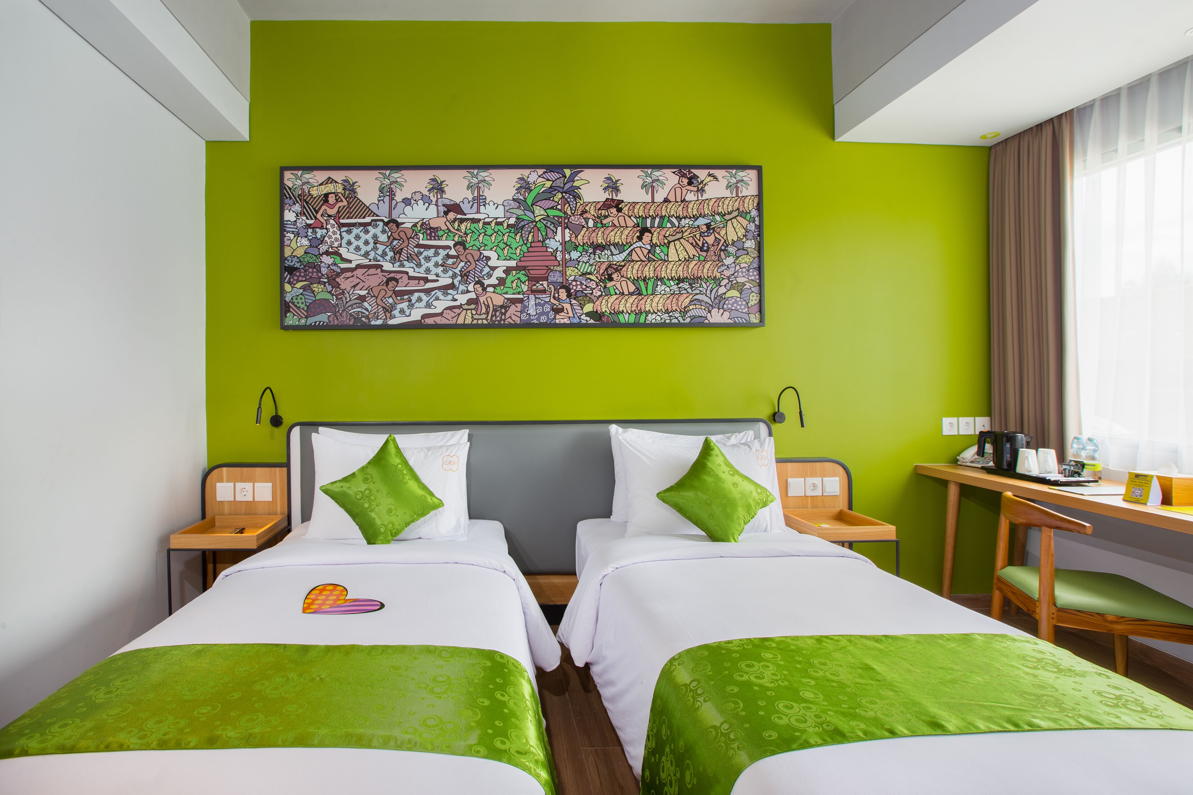 Quarto de hotel com duas camas, uma escrivaninha e uma grande obra de arte colorida na parede.