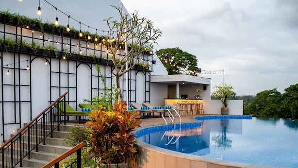 Un área de piscina moderna al aire libre con una escalera, un bar y un comedor.