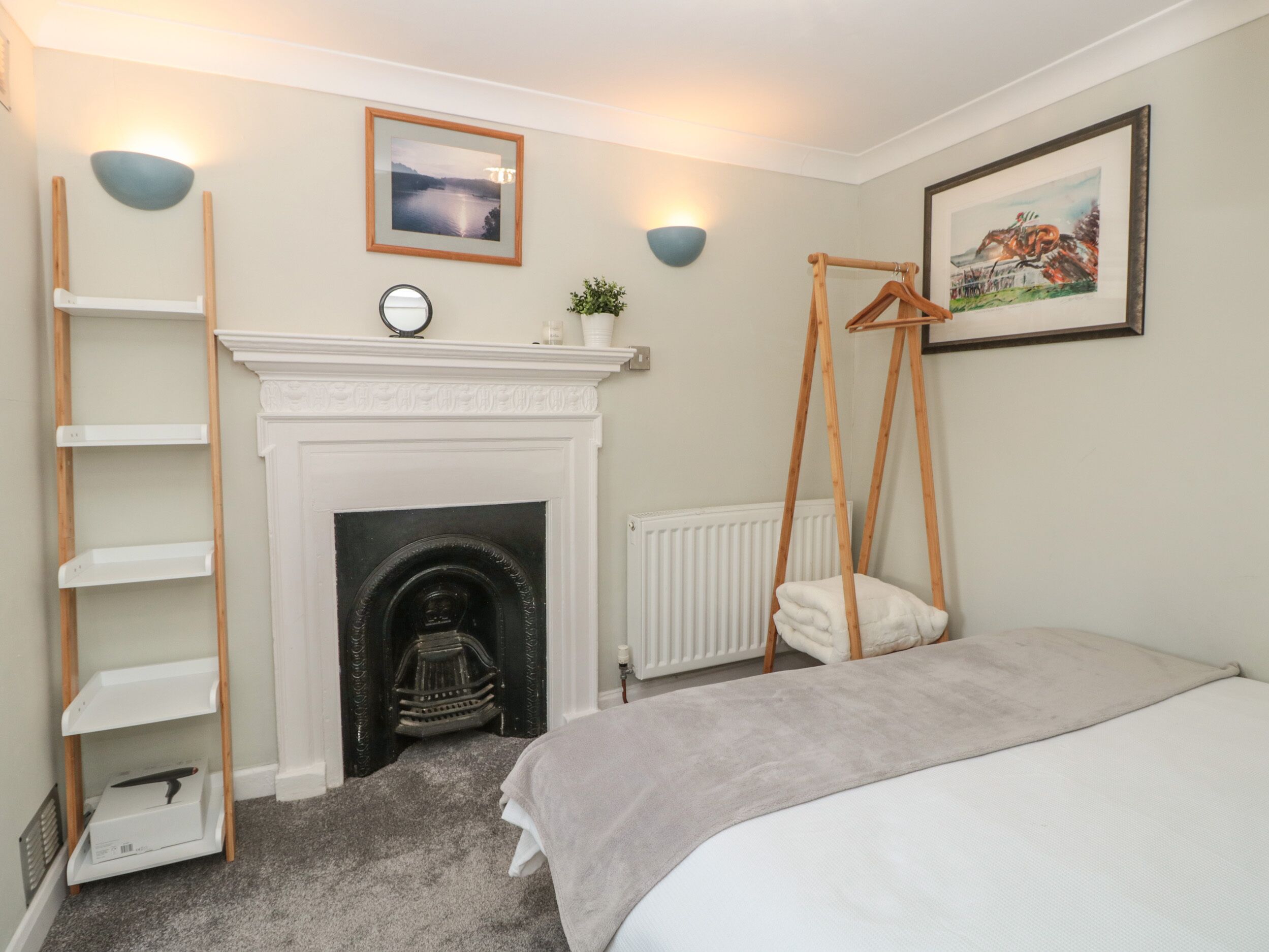 A bedroom with a fireplace, a bed, a ladder, and a radiator.