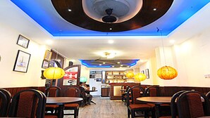 Un restaurant avec des banquettes et des tables, un éclairage bleu au plafond et des lanternes suspendues.