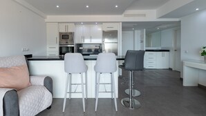 A modern kitchen with white cabinetry, stainless steel appliances, and a central island with bar stools. - Apartment 'Penthouse with private pool' with Sea View, Wi-Fi and Air Conditioning (Malaga)