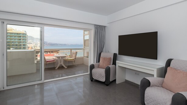 A modern hotel room with a balcony, a flat-screen TV, and a seating area with two armchairs. - Apartment 'Penthouse with private pool' with Sea View, Wi-Fi and Air Conditioning (Malaga)