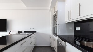A modern kitchen with white cabinetry, stainless steel appliances, and a black countertop. - Apartment 'Penthouse with private pool' with Sea View, Wi-Fi and Air Conditioning (Malaga)