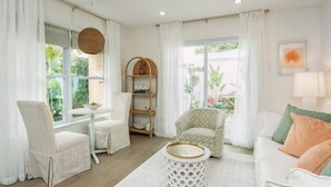 Un salon lumineux, avec des meubles blancs, une table ronde et une bibliothèque.