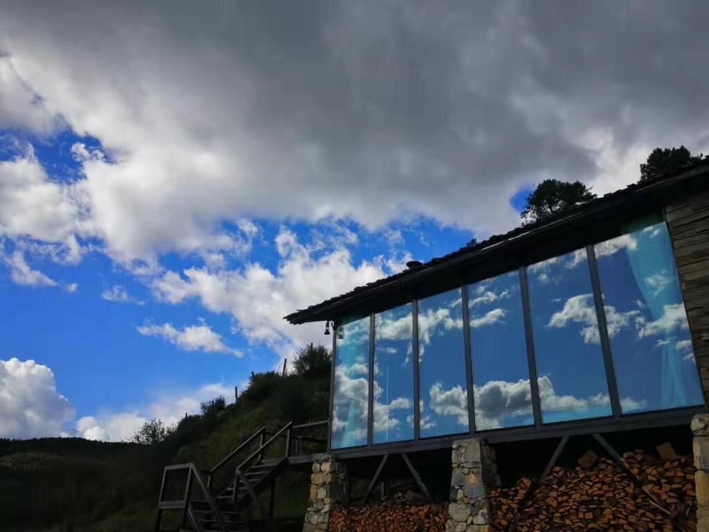 Een gebouw met grote glasramen die de lucht en wolken weerspiegelen.