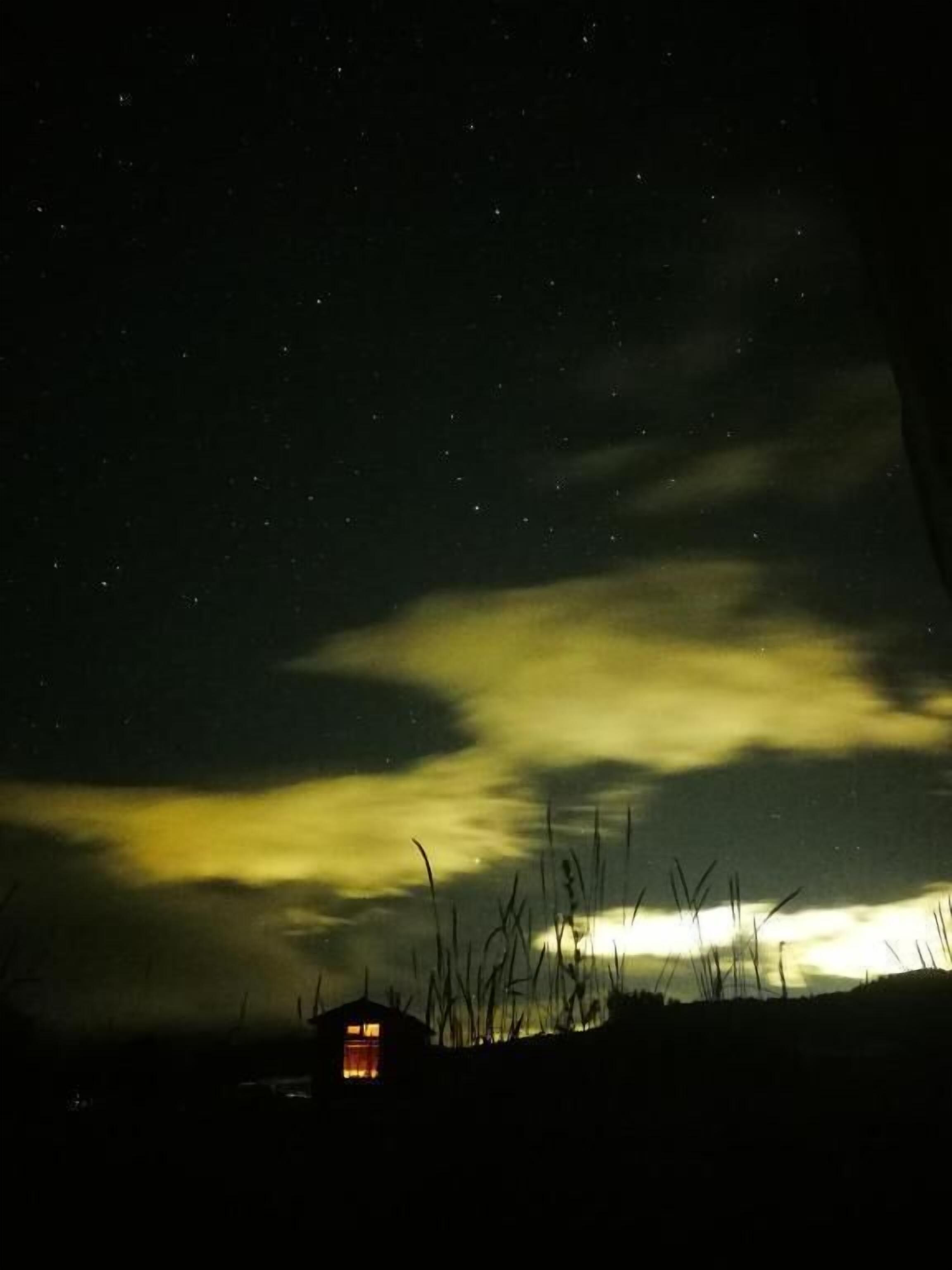 A night sky with stars and clouds.