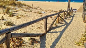 Un sentier en bois mène à une plage sous un ciel dégagé.