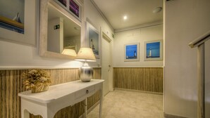 Une salle de bain d’hôtel avec un meuble-lavabo blanc, un miroir, une lampe et deux tableaux encadrés accrochés au mur.