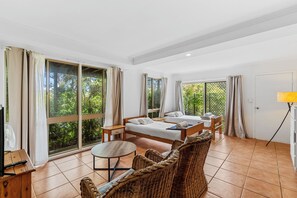 A room with two beds, a small table, wicker furniture, and large windows with curtains. - 20 Yarrong Rd - a very large house split over three levels (Point Lookout)