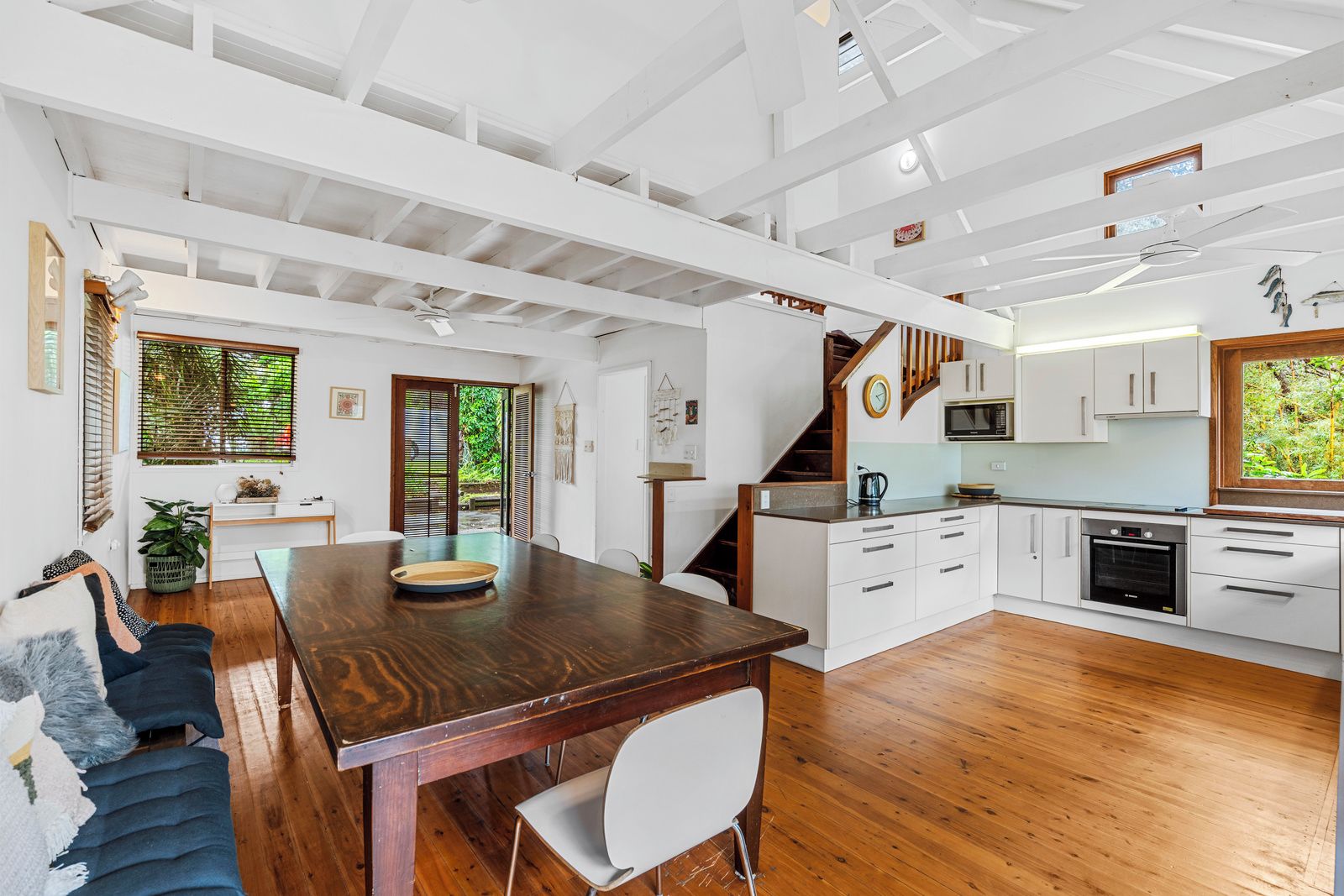 Une cuisine spacieuse avec un plancher en bois, des meubles blancs et un four encastré.