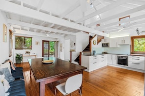 A spacious kitchen with wooden flooring, white cabinetry, and a built-in oven. - 20 Yarrong Rd - a very large house split over three levels (Point Lookout)