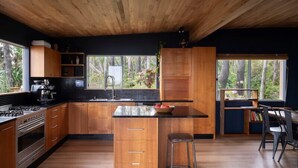 A modern kitchen with wooden cabinets, a central island, and a view of the outdoors. - Norm’s Place - a secluded, unique, absolute water front property at Amity Point (Amity Point)