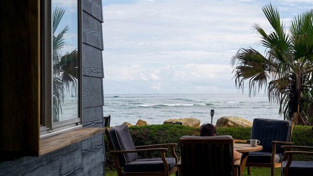 A patio with wooden furniture overlooking the ocean. - Norm’s Place - a secluded, unique, absolute water front property at Amity Point (Amity Point)