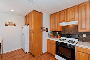 A kitchen with wooden cabinets, a white refrigerator, a gas stove, and a tiled backsplash.