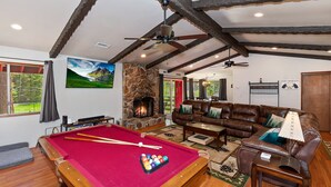 A cozy living room with a pool table, leather sofa, and a stone fireplace. - The Ginger Lodge By Destination Big Bear: Walking Distance to Meadow Park! Spa! Close to Snow Summit! Pool Table! (Big Bear Lake)