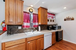 A kitchen with wooden cabinets, a white countertop, a dishwasher, and a microwave.