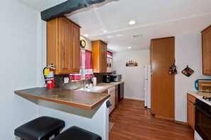 Una cocina compacta con gabinetes de madera, una isla integrada con asientos, un refrigerador y un microondas.