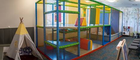 A play area enclosed by a colorful playpen with a small tent and a carpeted floor.