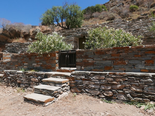 Un bâtiment aux murs de pierre, doté d’une porte en bois et d’un escalier menant à l’entrée.