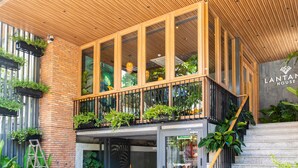 Un bâtiment moderne doté d’une façade en bois, de grandes fenêtres et d’un escalier menant à un balcon agrémenté de plantes.