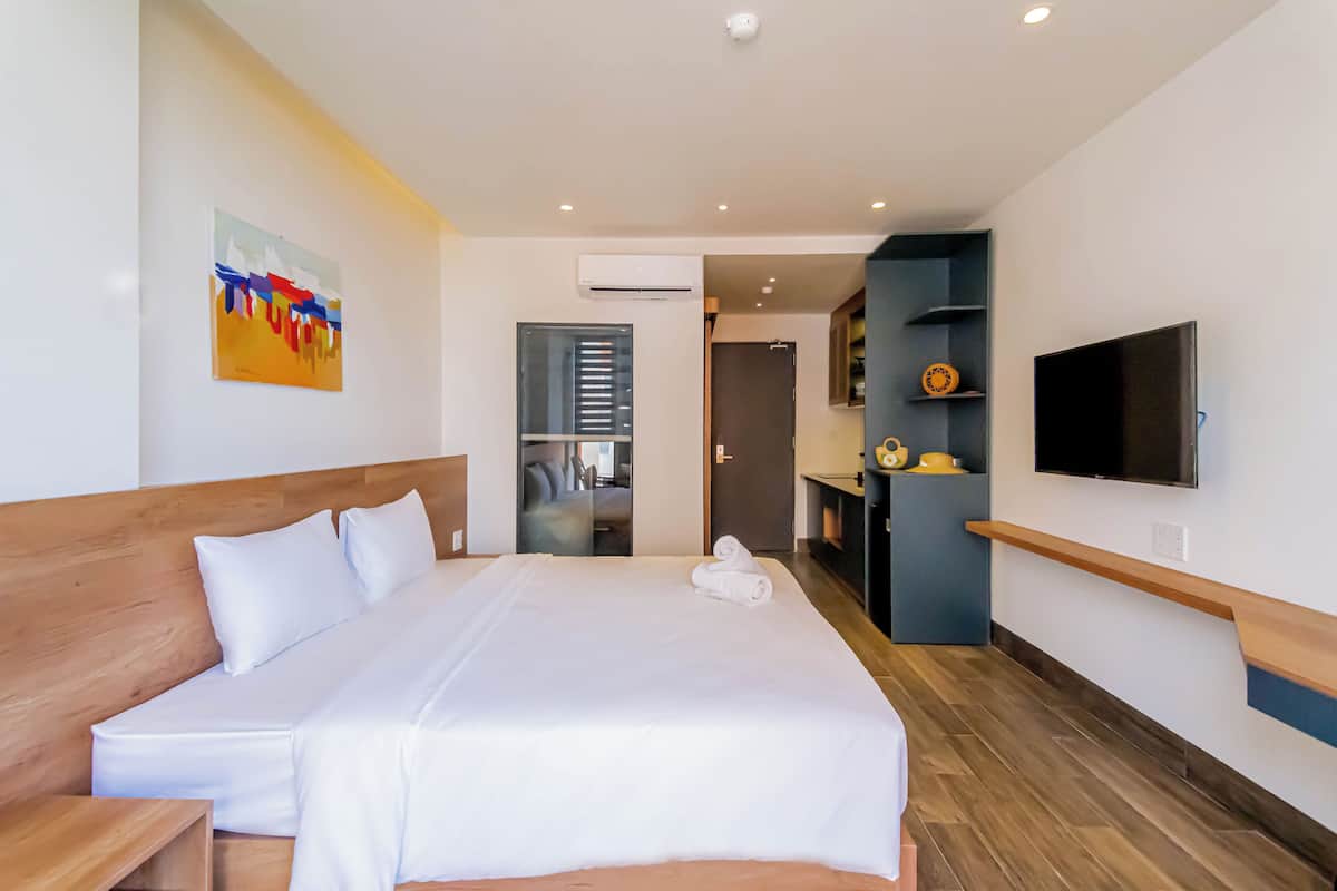 Ein modernes Hotelzimmer mit einem großen Bett, einem flachbildfernseher an der Wand und einem Holz-Kopfteil.