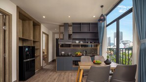 Eine moderne Küche mit integrierten Geräten, ein Essbereich mit Holztisch und Stühlen sowie ein Blick auf die Stadt durch große Fenster.