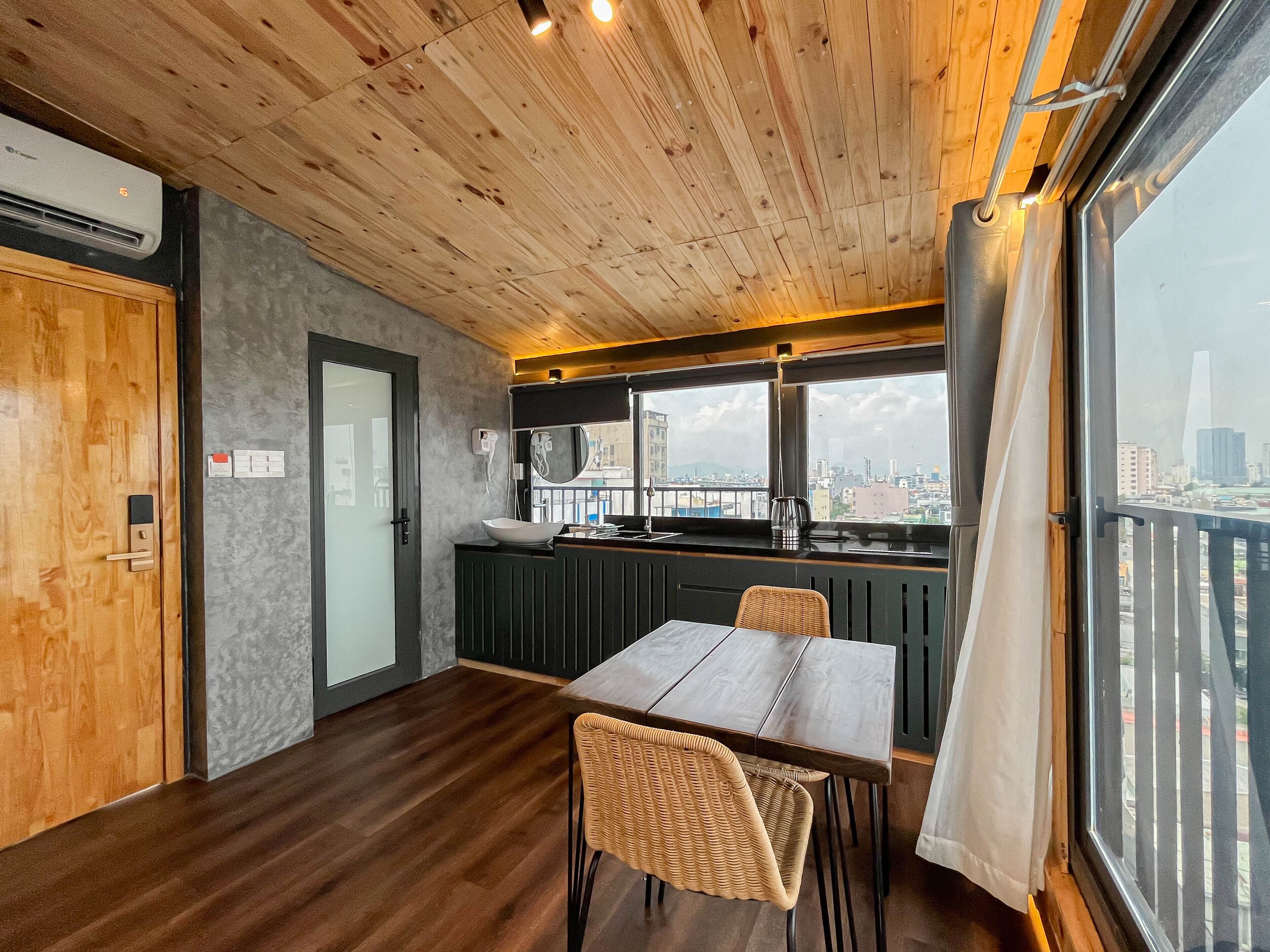 A modern kitchen with a large window, wooden ceiling, and a dining area with a table and chairs.