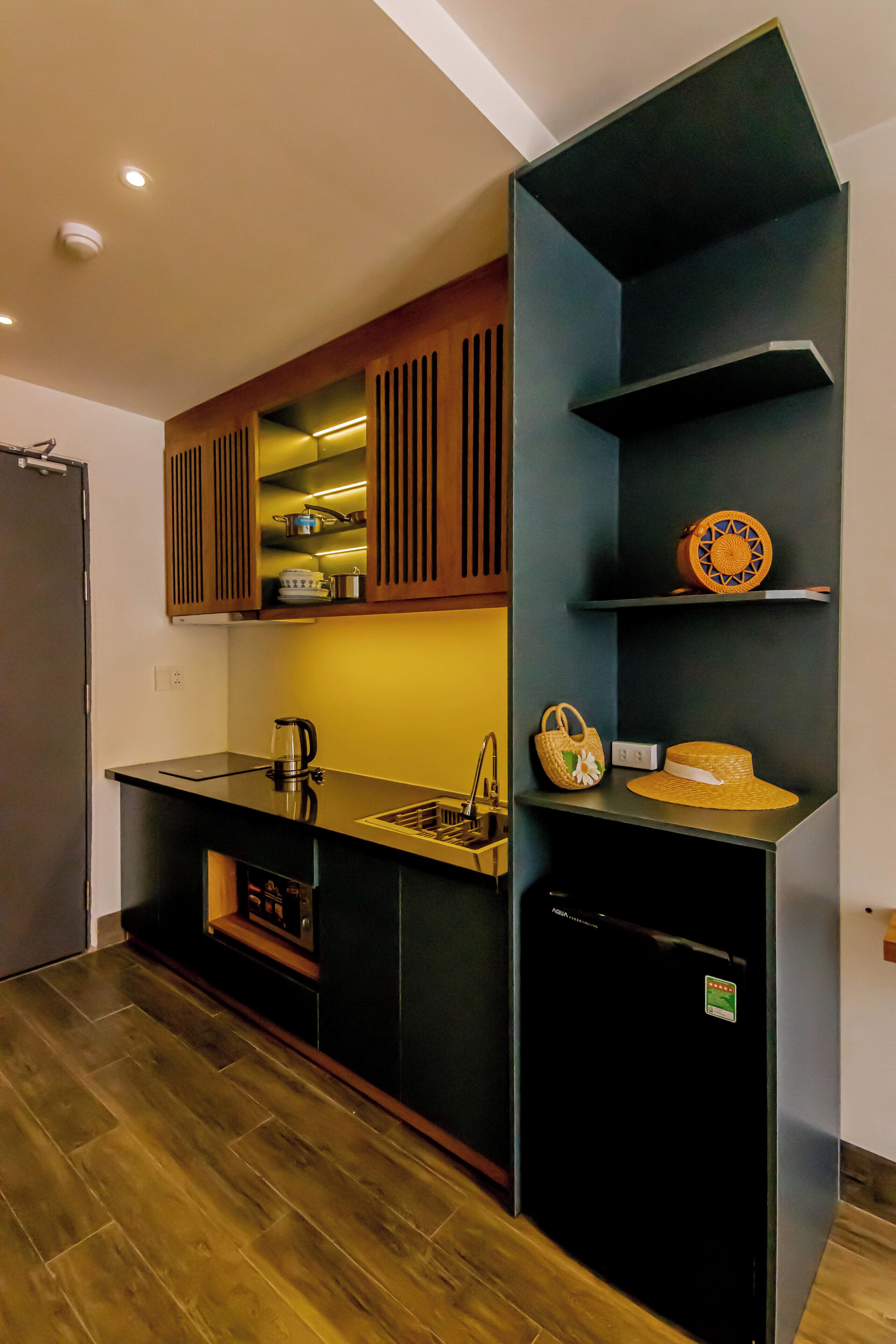 Une cuisine compacte dotée d’appareils électroménagers intégrés, de meubles de rangement en bois et d’un réfrigérateur noir.