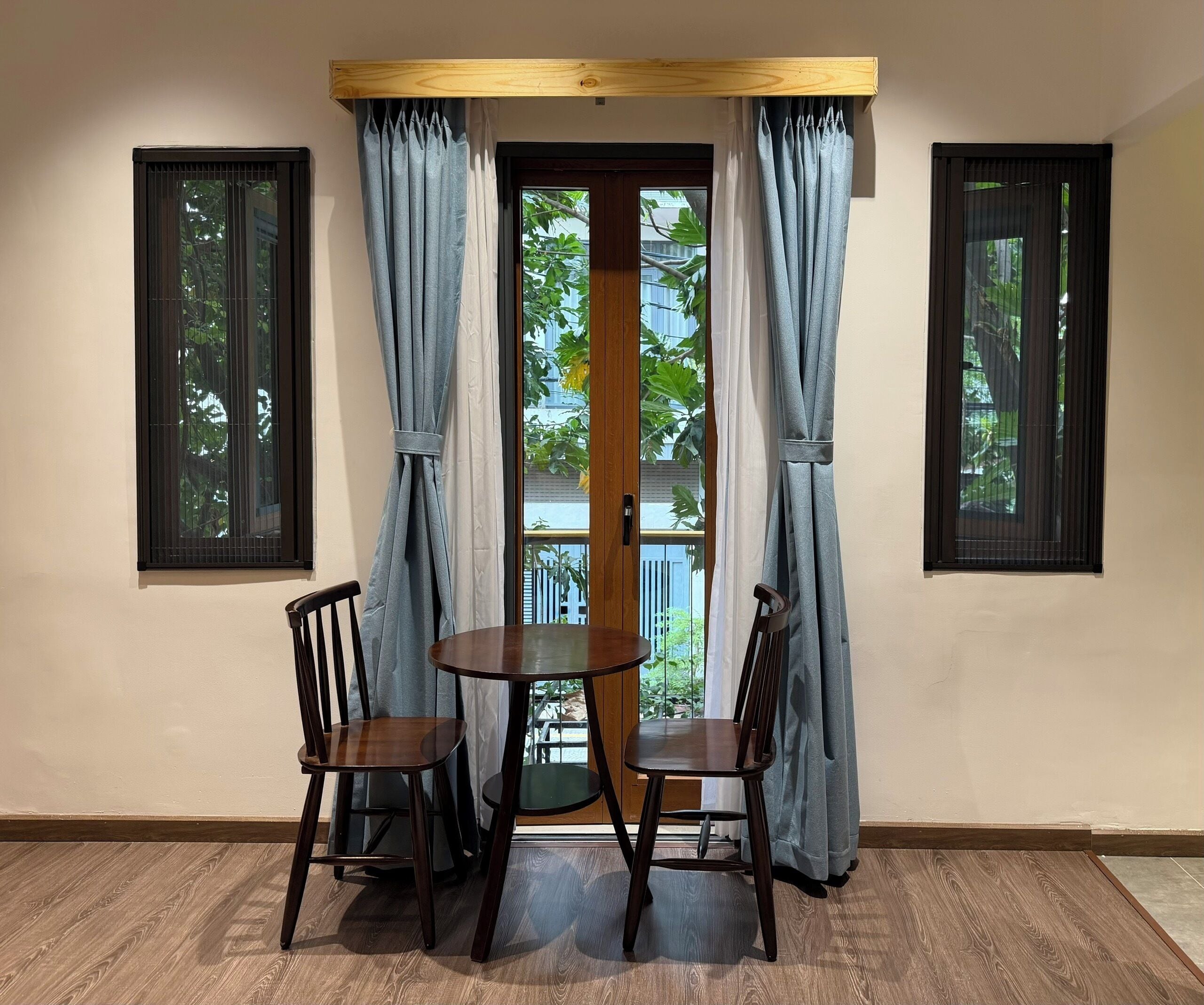 A corner room with two wooden chairs, a small round table, and a window with curtains.
