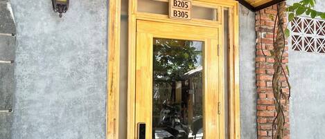 A wooden door with a glass panel, a small overhang, and a sign above it.