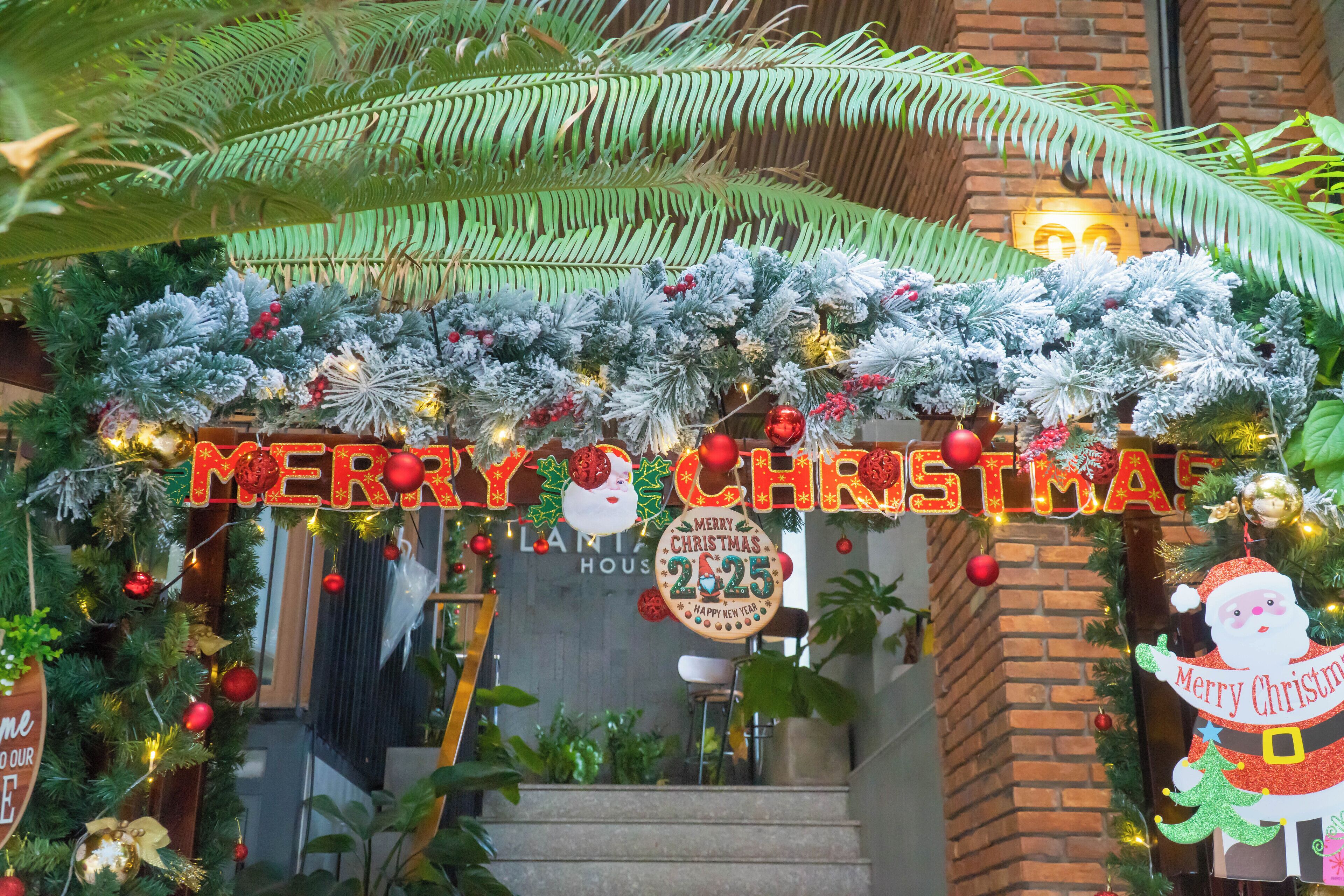 A decorated entrance with a 'Merry Christmas' sign, a Santa Claus figure, and a 'Merry Christmas 2025' banner.