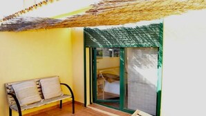 A small balcony with a bench, a door leading to a room, and a thatched roof. - Atenas Jávea (Jávea)