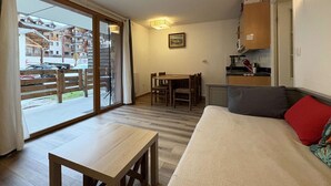 A compact living space with a dining area, kitchenette, and a large sliding glass door leading to an outdoor area. - Ski-In/Ski-Out Studio with Pool Access at Les Orres 1800 (Les Orres)