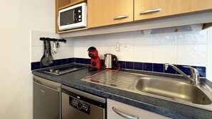 A compact kitchen with a dishwasher, a microwave, a kettle, and a sink. - Ski-In/Ski-Out Studio with Pool Access at Les Orres 1800 (Les Orres)