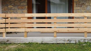 A wooden bench in front of a stone wall and a glass door. - Ski-In/Ski-Out Studio with Pool Access at Les Orres 1800 (Les Orres)