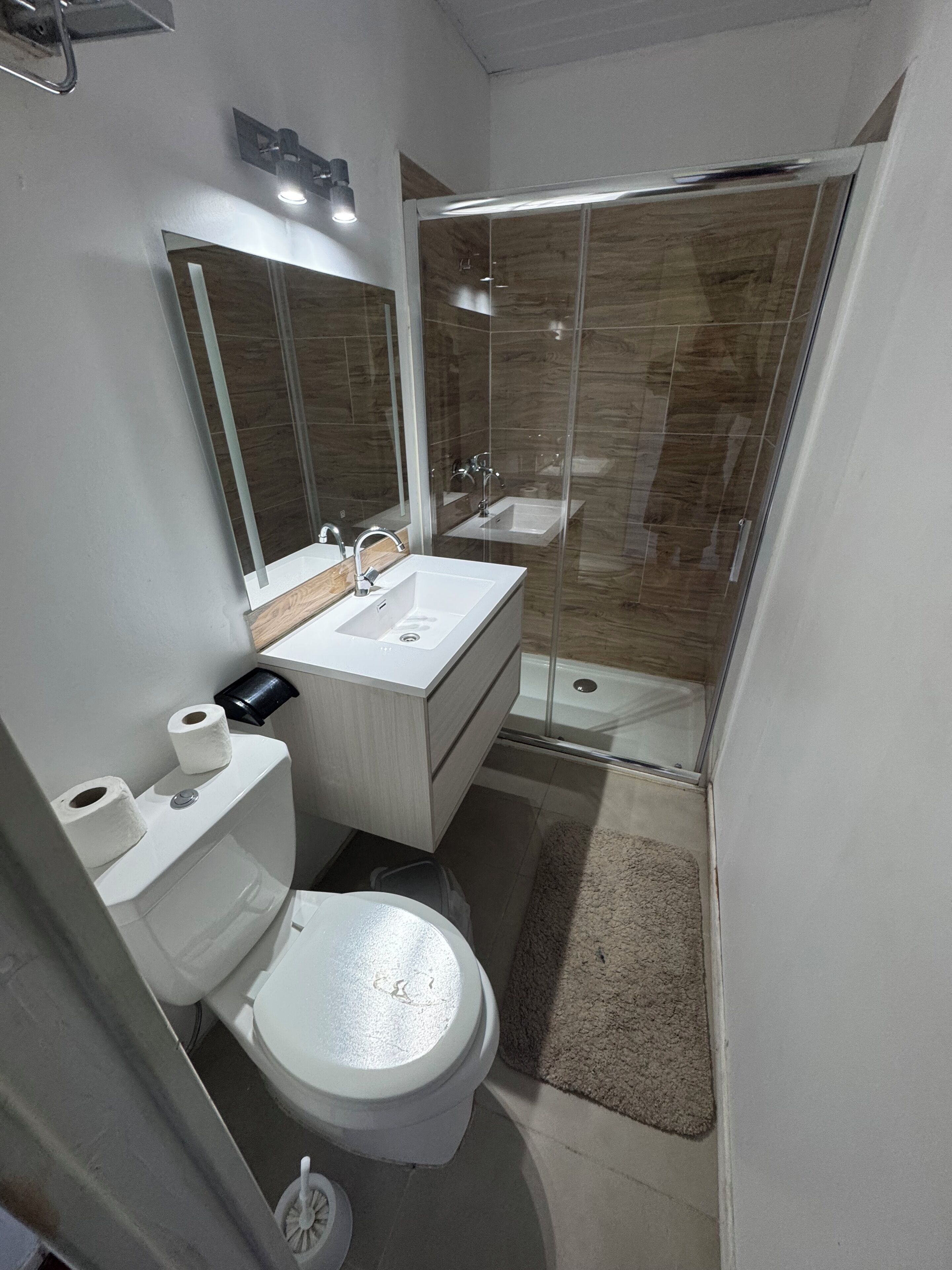 Un baño moderno con inodoro, lavamanos y ducha.